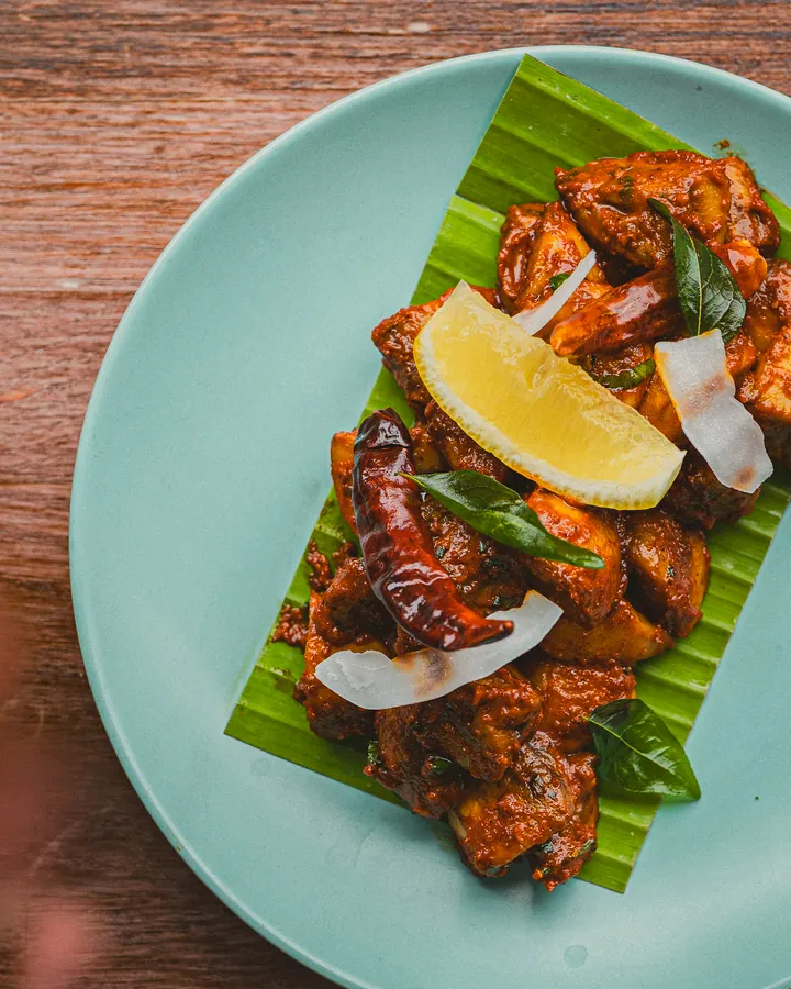 Fried chicken with lemon, coconut and curry leaves on a piece of banana leaf