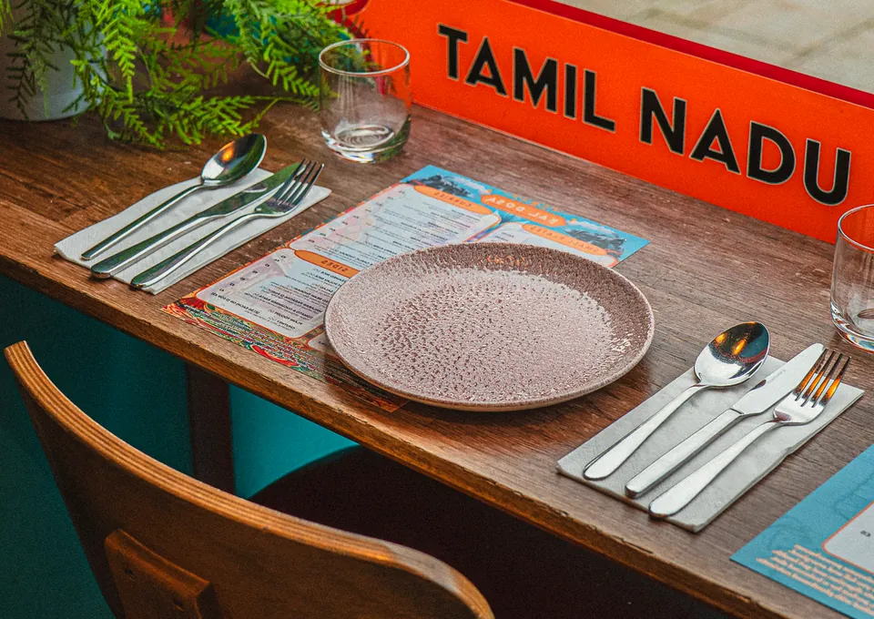 A table for two in the window, under the orange Tamil Nadu sign